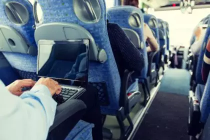 man with smartphone and laptop in travel bus